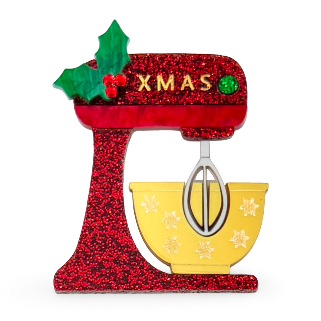 Decorative Christmas brooch shaped like a red glittery mixer with a yellow bowl and 'XMAS' text.